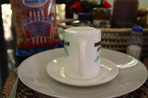 une tasse blanche assise sur une assiette sur une table dans l'établissement My Moka Arusha, à Arusha