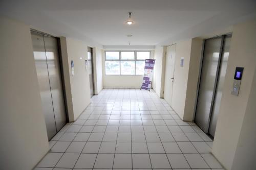 an empty hallway of an office building with doors and a tile floor at ARBA Dramaga Tower by Rendirooms in Bogor
