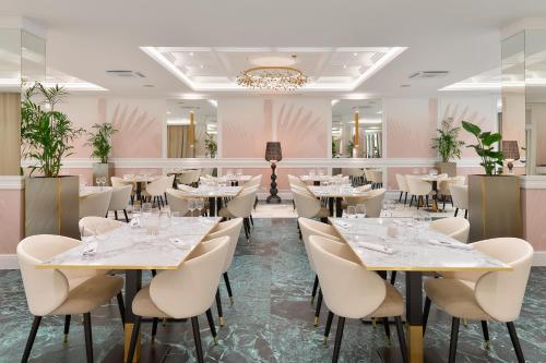 a restaurant with tables and chairs in a room with pink walls at Hotel Olympia Sky in Vodice