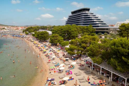 a group of people on a beach with a building at Hotel Olympia Sky in Vodice