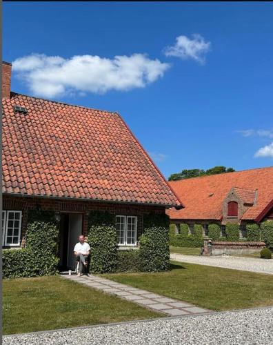 a man standing outside of a house with a dog at Gatekeepers house in Svennerup