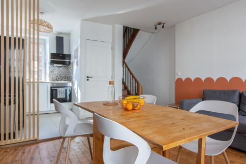 une cuisine et une salle à manger avec une table en bois et des chaises blanches dans l'établissement La Sirène - Entre châteaux et Beauval, à Romorantin-Lanthenay
