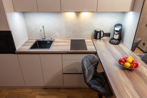 a kitchen with a sink and a bowl of fruit on a counter at Royal Hot Jucuzzi Apartment in Lviv