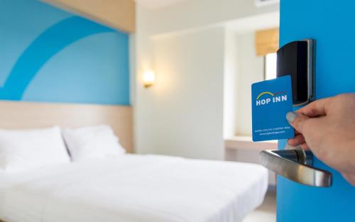 a person holding a door inn card in a hotel room at Hop Inn Ortigas Center Manila in Manila