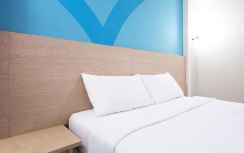 a bed with a white pillow in a room at Hop Inn Ortigas Center Manila in Manila