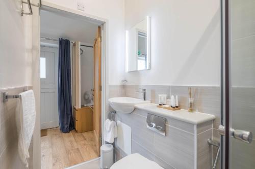 a white bathroom with a sink and a toilet at King Deluxe Ensuite with Courtyard View - Venn in Cambridge