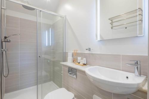 a white bathroom with a sink and a shower at King Deluxe Ensuite with Courtyard View - Hawking in Cambridge