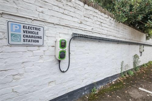 a sign on the side of a white brick wall with a phone at King Deluxe Ensuite with Courtyard View - Hawking in Cambridge