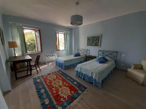 a bedroom with two beds and a table and a rug at Villa Pona in San Salvatore Monferrato