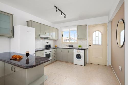 a kitchen with white cabinets and a washer and dryer at Oliva Poolside Residence by Nomads in Paphos