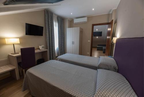 a hotel room with two beds and a desk at Apartments Torino Porta Susa PLUS in Turin
