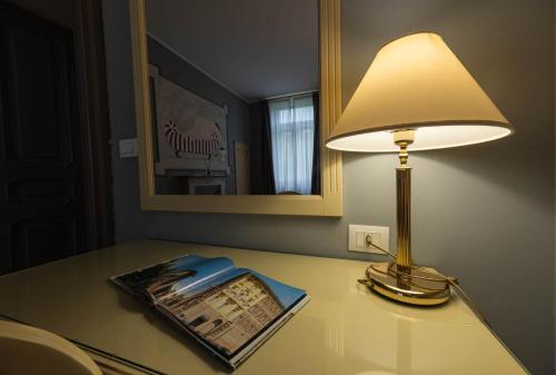 a lamp sitting on top of a table with a book at Apartments Torino Porta Susa PLUS in Turin