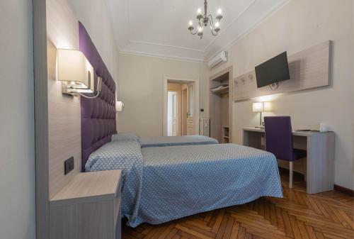 a hotel room with two beds and a desk at Apartments Torino Porta Susa PLUS in Turin