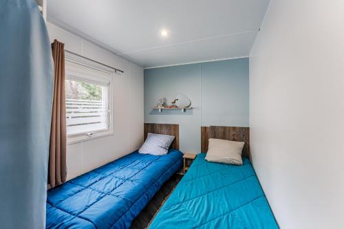 deux lits dans une chambre avec une fenêtre dans l'établissement Bungalow 2 Chambres Avec Clim, à Saint-Julien-en-Born