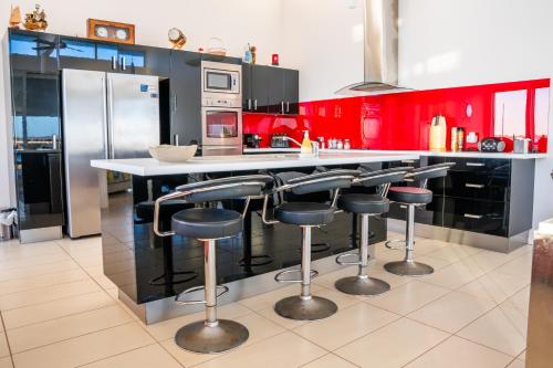 a kitchen with red cabinets and a counter with stools at Pelican Point Waterfront Resort in Carnarvon