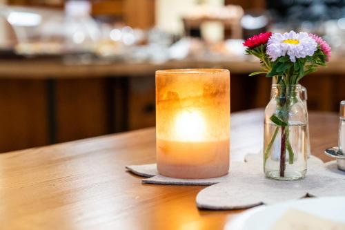 a candle and a vase with flowers on a table at Hotel Rietzer Hof in Rietz