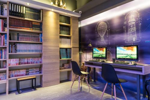 Taipei Discover Hostel في تايبيه: مكتبة بها مكتبين للكمبيوتر وأرفف الكتب