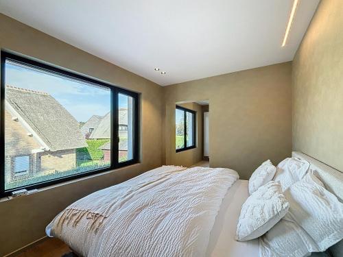 a bedroom with a bed and a large window at Villa Hélène - 2 newly renovated flats for rent together or separately in Koksijde
