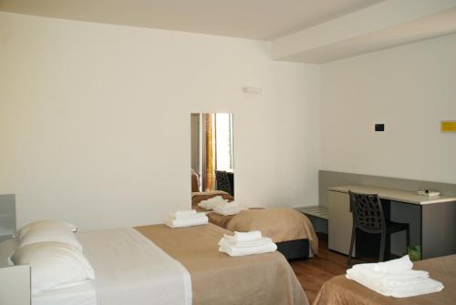 a hotel room with two beds and a desk at B&B Il Giardino di Circe - Filadelfia (VV) in Filadelfia