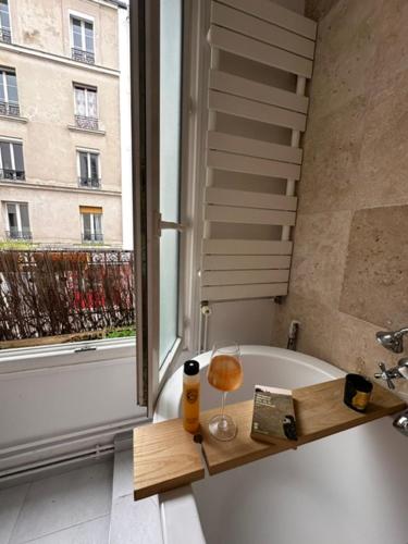 La salle de bains est pourvue d'une baignoire et d'une fenêtre. dans l'établissement Art House bastille 2 bed apartment w balcony, 11eme super trendy neighbourhood, à Paris