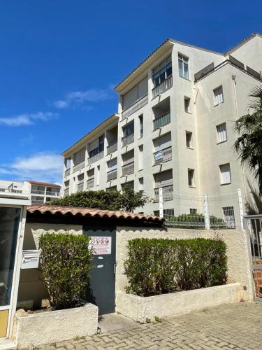 un grand immeuble avec des buissons en face dans l'établissement Cap près port commerces, au Cap d'Agde