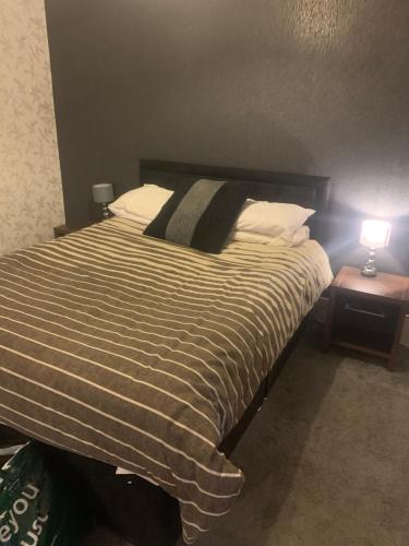 a bed with a striped comforter in a bedroom at The New Macleods Guest House in Blackpool