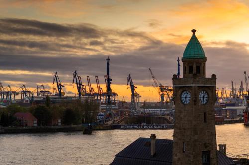 a clock tower with a green top on a river at Hotel Commerz Hamburg in Hamburg