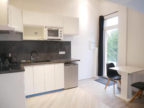 une cuisine avec des armoires blanches et un micro-ondes dans l'établissement Villa Cathy Studio Terrasse Léane, à Aix-les-Bains