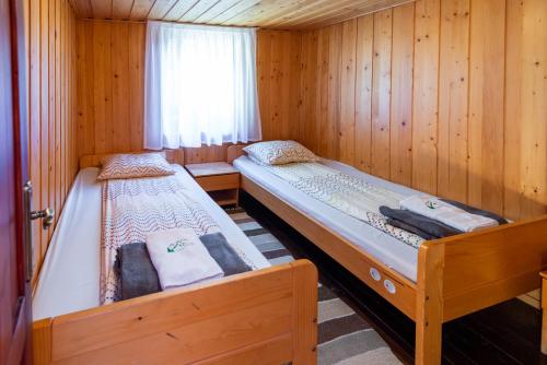 two beds in a room with wooden walls at Natura BH in Izvoare