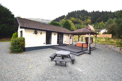 a house with a picnic table and a pavilion at Crann Mhor Holiday Home in Lochgoilhead