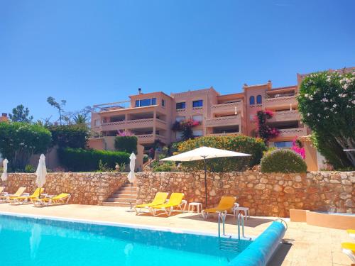 a swimming pool with chairs and umbrellas and a building at Apartamentos Turísticos Buganvilia in Lagos