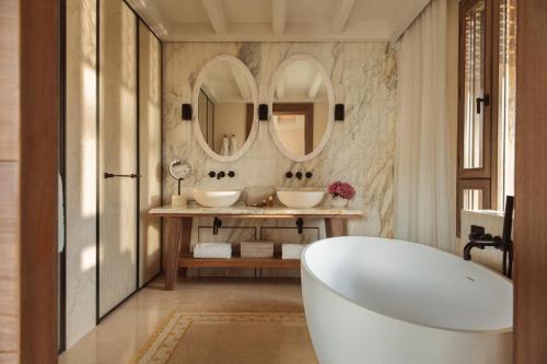 a bathroom with two sinks and two mirrors at Royal Mansour Tamuda Bay in M'diq