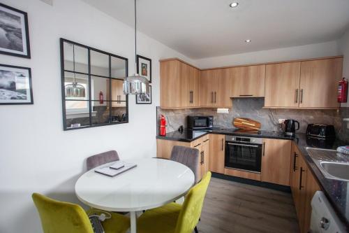 a kitchen with a white table and yellow chairs at Modern 3 Bed Flat Balloch in Jamestown