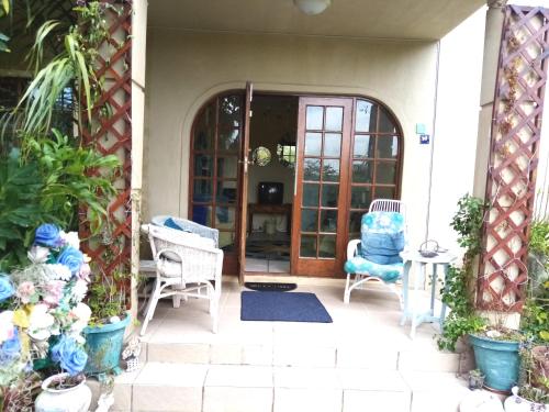 a patio with two chairs and an open door at Sea Valley Villa in Port Alfred