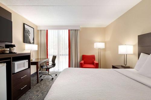 a hotel room with a bed and a desk and a chair at Ramada by Wyndham Alpena in Alpena
