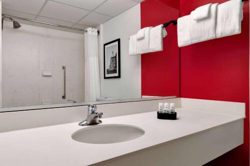 a bathroom with a sink and a red wall at Ramada by Wyndham Alpena in Alpena