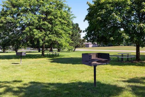 a park with picnic tables and trees in the grass at Ramada by Wyndham Alpena in Alpena