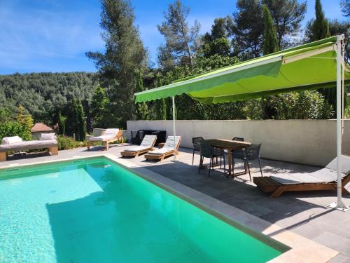 - une piscine avec des chaises, une table et un parasol vert dans l'établissement La Villa des Rouvières, à LʼÉtoile