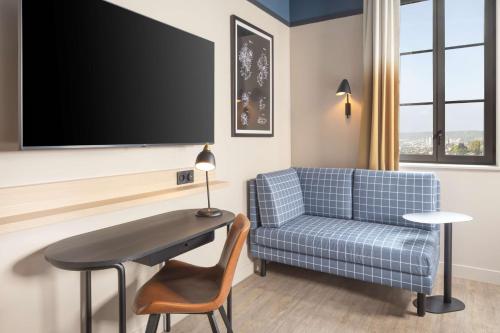 a living room with a blue couch and a table at Hyatt Place Rouen in Rouen