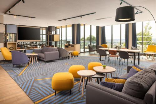a living room with yellow chairs and tables at Hyatt Place Rouen in Rouen