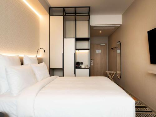 a bedroom with a large white bed and a television at Mercure Szczyrk Resort in Szczyrk