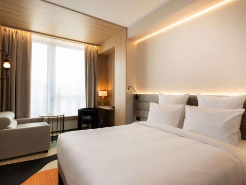 a hotel room with a large white bed and a chair at Mercure Szczyrk Resort in Szczyrk