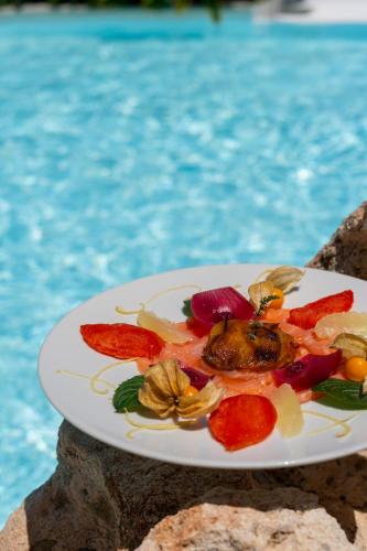 a plate of food on a table next to a pool at Hotel Sa Pedra in Murta Maria