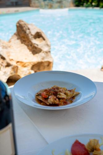 a plate of food on a table next to a pool at Hotel Sa Pedra in Murta Maria