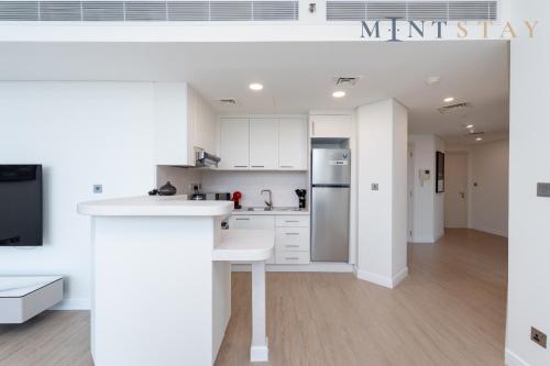 a kitchen with white cabinets and a refrigerator at Sky Gardens, Park Avenue, DIFC - Mint Stay in Dubai