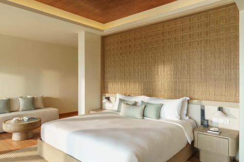 a bedroom with a large white bed and a couch at Huvafen Fushi Maldives in North Male Atoll