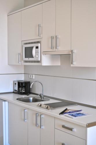 a white kitchen with a sink and a microwave at El Secreto del Agua in Mar de Cristal