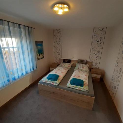 a bedroom with a bed with blue sheets and a window at Ferienwohnung Hof Postel in Hemmoor