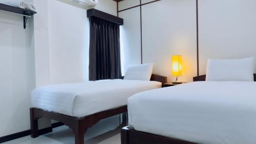 a room with two beds and a table with a lamp at EZ House in Sukhothai