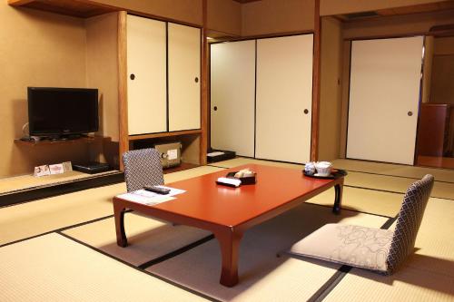 a room with a table and two chairs and a television at Suimeikan in Gero